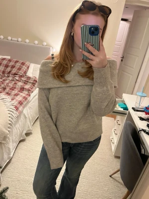 Beige offshoulder stickad tröja H&M - Supermysig beige stickad tröja från H&M i offshoulder-modell. Tröjan har bred krage som vilar över axlarna och långa ärmar med ribbade muddar. Perfekt att styla med jeans eller kjol för en chill look. Materialet är mjukt och ger en skön känsla.