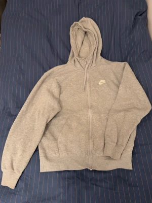 Grå Nike kofta i klassisk design med dragkedja  - Koftan har en hel dragkedja, huva med dragsko och två framfickor 