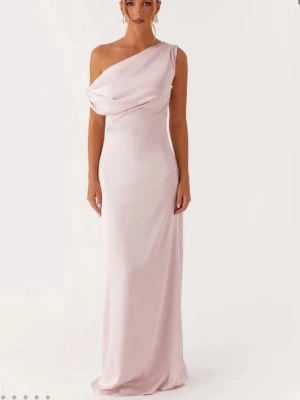 Ljusrosa  långklänning i satin till bal  - Elegant ljusrosa långklänning i satin med draperad överdel och oneshoulder-design. Perfekt för bal eller festliga tillfällen. Helt ny med prislapp på! Från det trendiga australiensiska märket: peppermayo!