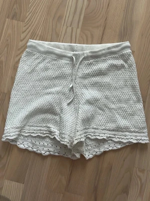 Vita virkade shorts med snörning - Säljer dessa sjukt snygga virkade shorts med snörning i midjan och fina virkade detaljer längst ner. De har en relaxed fit och är perfekta för sommaren!!😍😍