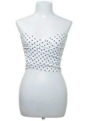 Vit prickig bandeau tubtopp - Säljer en vit bandeau tubtopp med svarta prickar. Toppen är axelbandslös och har en draperad, figurnära passform som ger en snygg siluett. Perfekt till sommarens alla outfits och enkel att matcha med både jeans och kjol.
