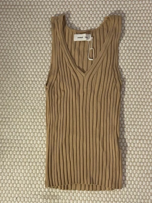 Beige ribbad linnetopp Samsøe Samsøe - Säljer en beige ribbad linnetopp från Samsøe Samsøe. Toppen har v-ringning, är ärmlös och har en figurnära passform. Materialet är mjukt och stretchigt. Enkel och stilren design som är lätt att matcha.