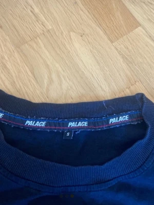 Svart Palace tshirt - Snygg svatt t-shirt från Palace med klassisk passform och liten bröstficka med Palace-logga. Skön rund halsringning och korta ärmar. Perfekt till streetwear-stilen och enkel att matcha med allt.