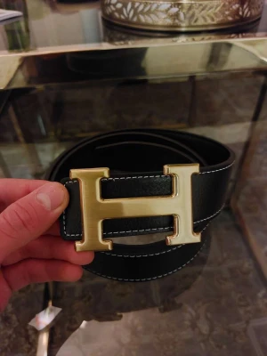 H bälte svart guld  - ● Ny och aldrig använt. Litet verktyg för att göra hål med är inkluderad 👍  ● Storlek: 115cm.   ● Fraktar inom 24h, så att du får paketet så fort som möjligt! 📦 Vid frågor eller intresse, dm. 😁