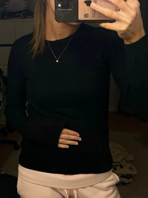 Svart stickad tröja med lång ärm - En enkel och stilren svart stickad tröja med rund halsringning och långa ärmar. Perfekt basplagg som passar till det mesta och är lätt att matcha med olika outfits.