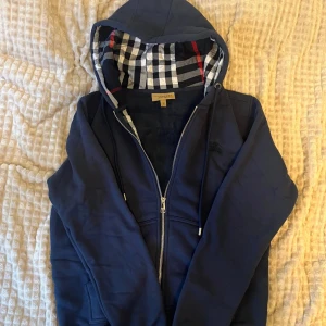 Marinblåa BURBBERY hoodie  - Säljer en tvärfet burberry hoodie. Perfekt för kyliga dagar och snygg till jeans. Passar även M. Några funderingar skriv då till mig! Priset är inte hugget i sten. 