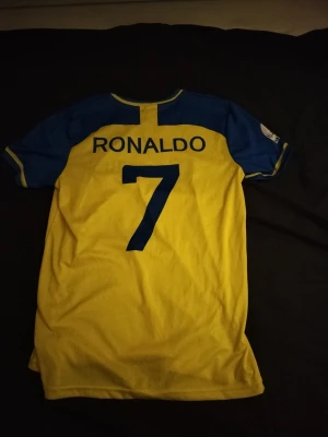 Al Nassr tröja med Ronaldo på ryggen - Det är en Al Nassr tröja med Ronaldo på ryggen den är gul och blå