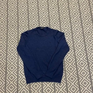 Mörkblå stickad tröja från J.Lindeberg - Obs!! Tröjan är i storlek M men har krympt i tvetten och passar som xs, kanske lite mindre!!!!Säljer en stilren mörkblå tröja från J.Lindeberg i mjuk ull. Tröjan har rund halsringning, diskret JL-logo på bröstet och långa ärmar. Perfekt för lager-på-lager och funkar lika bra till jeans som till chinos.