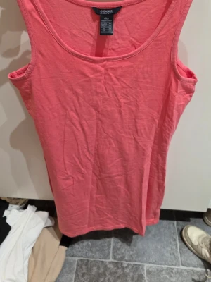 Korallfärgad linnetopp från Ellos - Säljer en snygg korallrosa linnetopp från Ellos, modell e-Basics. Toppen är ärmlös med rund halsringning och tillverkad i mjuk bomull med lite stretch för skön passform. Perfekt för varma dagar och enkel att matcha med jeans eller shorts.