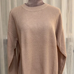 Rosa stickad tröja med slits - Säljer en rosa stickad tröja med långärmad design och rund hals. Tröjan har en snygg slits på sidorna som ger en cool detalj och extra rörelsefrihet. 