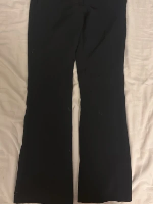 Svarta bootcut kostymbyxor - Snygga svarta kostymbyxor med bootcut passform. Byxorna har en klassisk look med raka ben som blir vidare nedtill. Perfekta att styla med sneakers eller boots för en clean vibe.
