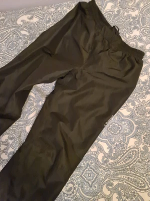 Svarta täckbyxor från Everest 158/164 - Svarta täckbyxor från Everest i storlek 158/164. Byxorna har elastisk midja och är gjorda i ett slitstarkt syntetmaterial som står emot väta och kyla. Perfekta för kalla dagar och utomhusaktiviteter. Snyggt Everest-tryck på benet. Vattentåliga, även varma men mer i syfte för regn o slask än kyla. Cirka använd 3 gånger