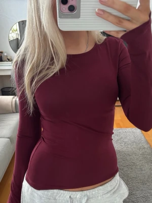 Vinröd långärmad topp från Gina Tricot - Säljer en enkel och stilren vinröd långärmad topp från Gina Tricot i storlek XS. Toppen har rund halsringning och är figurnära i passformen. Materialet är mjukt och stretchigt, perfekt att matcha med jeans eller kjol. Använd 2 gånger.