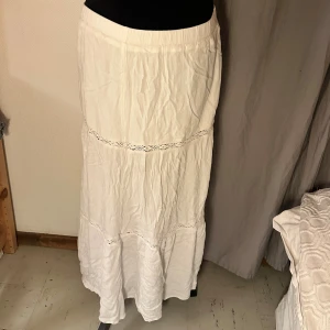 Vit långkjol från H&M DIVIDED - Säljer en vit långkjol från H&M DIVIDED med snygga spetsdetaljer och lätt rynkad struktur. Kjolen har resår i midjan och är tillverkad i ett mjukt bomullsmaterial som känns skönt mot huden. Perfekt för dig som gillar en boho-vibe och vill ha något luftigt.