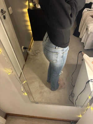 Ljusblå slitna jeans från Lindex - Säljer ett par ljusblå jeans från Lindex med snygga slitningar på båda benen och klassisk femficksdesign. Jeansen har låg midja och raka ben med lite bootcut-vibe. Perfekt för dig som gillar en avslappnad och cool stil.