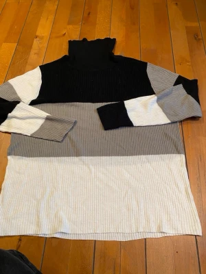 Randig polotröja från Brave Soul - Säljer en ribbad polotröja från Brave Soul i svart, grått och vitt. Tröjan har lång ärm och breda blockränder som ger en cool look. Perfekt för dig som gillar stilrena färger och vill ha något som sticker ut lite extra.