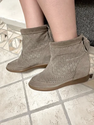 Beige boots från Isabel Marant med tofs - Säljer ett par beige/grå boots från Isabel Marant i mocka med fint mönster och dekorativ tofs baktill. Klacken är ca 6 cm.  Perfekt för dig som gillar snygga detaljer och stilren design.💋