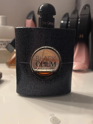 YSL Black Opium parfym - Trendig parfym från Yves Saint Laurent med ikonisk design. Perfekt för dig som vill sticka ut och addera en lyxig touch till din stil. 90ml flaska skulle säga att de är typ 30ml kvar ❤️