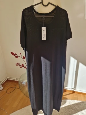 Svart långklänning i merinoull från Lindex - Svart långklänning från Lindex Premium i mjuk merinoull. Klänningen har rund halsringning, korta ärmar och en rak, loose passform. Perfekt för dig som gillar stilren och enkel design med fokus på komfort.