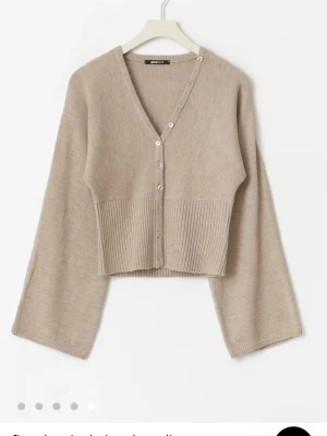 Beige kofta från Gina Tricot - Superfin beige kofta med v-ringning och knappar framtill. Köpt men har bara använt bara ett fåtal gånger