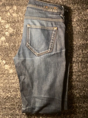 Diesel Floyj - Säljer ett par klassiska blå jeans från Diesel med snygga kontrastsömmar och detaljerade fickor. Jeansen har rak passform och normal midja, tillverkade i slitstarkt denim. Perfekta för dig som gillar en tidlös och avslappnad stil.