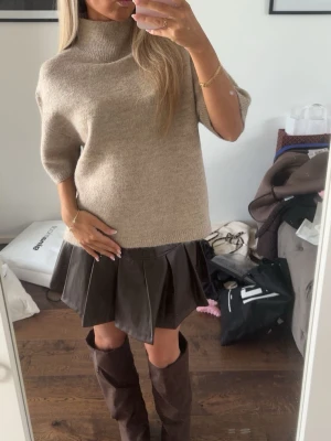 Beige polotröja i ullmix - Säljer en beige polotröja med halvkort ärm och lös passform. Tröjan är stickad i mjuk ullmix och har en hög polokrage som ger en chill vibe. Perfekt att styla med kjol eller jeans för en trendig look. Populär tröja från Gina tricot, använt fåtal gånger!!