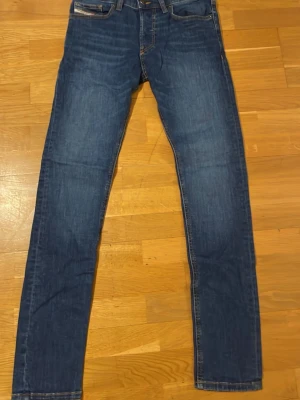 Diesel D-Luster slim jeans blå W28 L32 - Snygga blå jeans från Diesel, modell D-Luster med slim passform. Klassisk femficksdesign, kontrastsömmar och raka ben. Jeansen är tillverkade i slitstarkt denim och har en stilren look som funkar till många olika outfits.