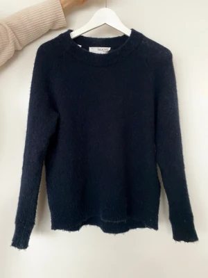 Marinblå stickad tröja  - Mysig mörkblå stickad tröja från Selected  Femma. Tillverkad i en mjuk mix av ull, alpacka, polyester, nylon och elastan. Upplever att den har tendens att noppra lite men inget jag har försökt göra något åt.