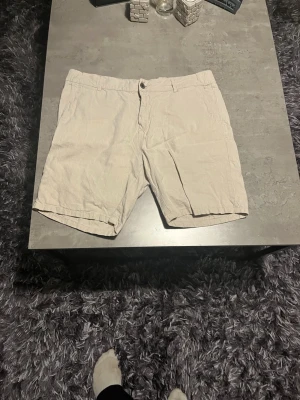 Beige linneshorts XL - Säljer ett par ljusbeige shorts från Cubus i storlek XL. De är tillverkade i linne, har normal passform, knapp och dragkedja framtill samt fickor både fram och bak. Perfekta för varma dagar och riktigt sköna att bära.