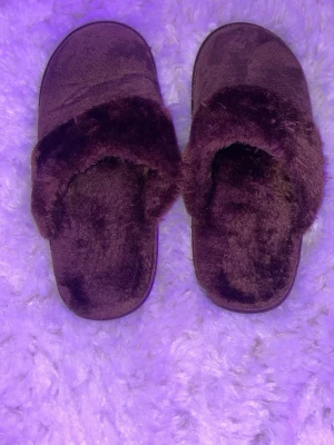 Bruna fluffiga sandaler - Mysiga bruna sandaler med fluffig pälsimitation över foten och på innersulan. Perfekta att glida runt i hemma när du vill ha det extra bekvämt. De har en platt sula och en öppen bakdel , vilket gör dem superenkla att ta på och av.