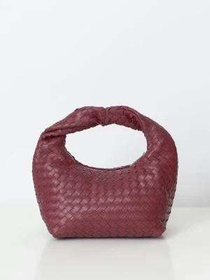 Väska gina tricot - Säljer en vinröd handväska med snygg flätad design och rundad form. Väskan är tillverkad i skinn och har ett mjukt handtag som gör den enkel att bära. Perfekt för dig som gillar stilrena detaljer och vill ha något som sticker ut.