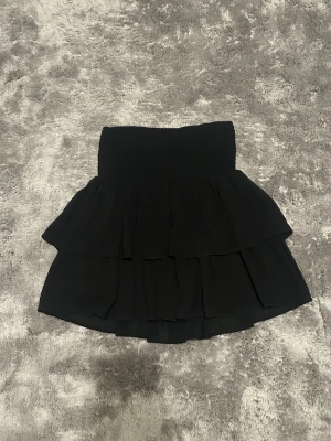 Svart kjol  - Volangkjol från Kappahls barnavdelning, storlek 170 men passar typ xs/s. Passar bra på sommaren eller till strumpbyxor. Använd mycket men ändå bra skick. Skriv för fler bilder 🩷