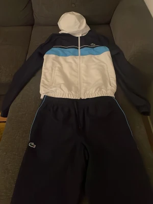 Lacoste tracksuit - Fet Lacoste tracksuit som jag inte behöver längre, köpt i september för 2860kr från JD. Tracksuit är knappt använd inget fel med byxorna eller överdelen. 