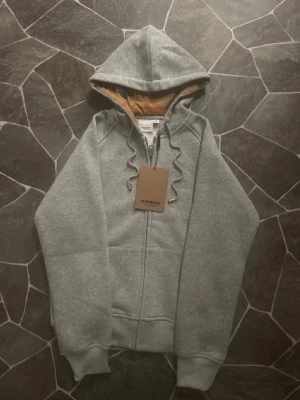 Burberry Zip - En mycket fin helt oanvänd zip ifrån Burberry. Tröjan har aldrig använts därmed har den inga defekter. Säljs pga en storlek mindre, sitter mer som S.                                                                     Priset kan diskuteras!