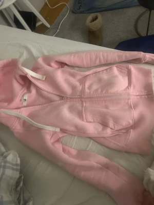 Rosa russemerch zip up hoodie - En fin zip up hoodie i en rosa fin färg med en tajt och stilren passform. Denna hoodie är köpt för 700 och är inte så mycket anvönd så säljer darför dyrt men kan diskutera pris!