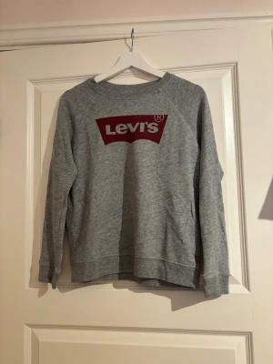 Grå sweatshirt från Levi's med röd logga - Grå sweatshirt från Levi's i storlek S med röd logga framtill. 