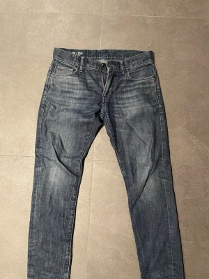 G-Star Raw 3301 Slim jeans blå - Säljer ett par G-Star Raw 3301 Slim jeans i riktigt fin mörkblå tvätt med snygga slitningar. Klassisk femficksmodell med dragkedja och knapp, samt diskreta detaljer på fickorna. Jeansen har en smal passform och är tillverkade i slitstarkt denimtyg. 