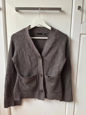 Brun stickad kofta från 157 XS - Mysig brun stickad kofta från 157 i storlek XS. Koftan har två framfickor, ribbade muddar och knäpps med tre knappar framtill, använd 2 gånger. Kommer ej till användning någon mer.😊