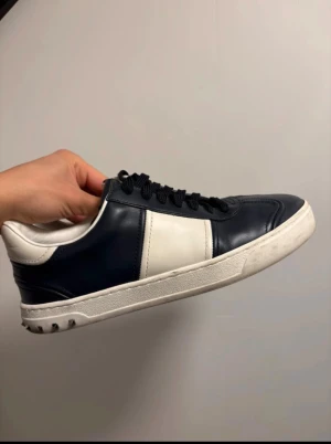 Valentino’s flycrews - Snygga Valentino flycrew sneakers i mörkblå läder med vita detaljer och platt sula. Skorna har snörning, rund tå och coola nitar på hälen. Märkeslogga på plösen och unik mönstrad yttersula. Perfekt för dig som gillar exklusiv streetstyle. Skriv om ni har frågor eller funderingar!😊