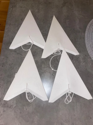 Vita pappersstjärnor med mönster 20kr styck - Fyra vita pappersstjärnor i triangelform med små prickmönster i spiralform. Varje stjärna har ett vitt snöre för upphängning. Perfekta som dekoration i fönster eller på väggen. Materialet är papper och de är helt vita. Går att köpa styckvis 
