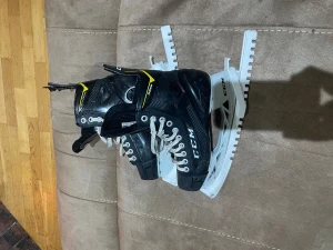 Svarta CCM hockeyskridskor 9366 - Säljer ett par svarta CCM hockeyskridskor modell 9366 med vita snören och Speedblade-stål. Skridskorna har detaljer i gult och vitt, högt skaft och robust konstruktion för extra stöd. Perfekt för dig som vill ha grymma skridskor på isen. Och skridskorskydd ingår 