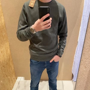  stickad tröja från Stenströms - Stilren mörkgrön stickad tröja från Stenströms. Tröjan har rund halsringning, ribbade muddar och är långärmad. Perfekt för dig som gillar klassisk och enkel stil. Materialet är mjukt och passar bra till jeans eller chinos. Mycket bra skick! 