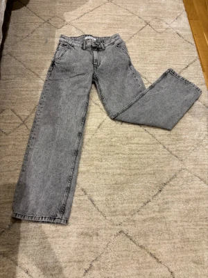 Gråa Calvin Klein jeans straight fit - Säljer ett par gråa jeans från Calvin Klein Jeans med raka ben och klassisk passform. Jeansen har broderad CK-logga på bakfickan och är tillverkade i denim. Perfekta för dig som gillar en clean och tidlös look.