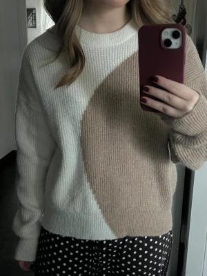 Beige och vit stickad tröja NA-KD - Säljer en snygg stickad tröja från NA-KD i storlek XS. Tröjan har ett coolt blockmönster i beige och vitt, rund hals och ribbade muddar. Perfekt för dig som gillar stilrena och trendiga plagg med lite extra edge.