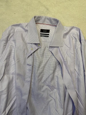 Ljus rutig skjorta från Eton - Snygg ljusblå/lila skjorta från Eton med diskret rutigt mönster. Skjortan har klassisk krage, knappar framtill och extra långa ärmar. Contemporary fit för en modern look. Tillverkad i mjuk bomull som känns skön mot huden.