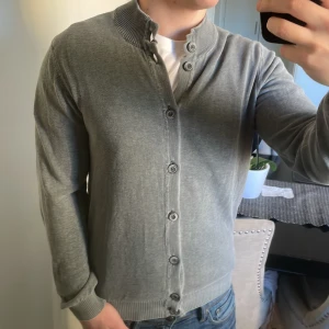Grå stickad cardigan - Otroligt fet grå stickad cardigan i unik färg design. Modellen är 180cm, 73kg. Priset kan såklart diskuteras!