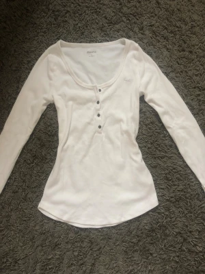 Vit långärmad tröja från Hollister - Säljer en henley tröja från hollister🥰Hör av dig vid minsta lilla fråga och om du är intresserad så rekommenderar jag att slå till så fort som möjligt för dessa tröjor är väldigt eftertraktade💕