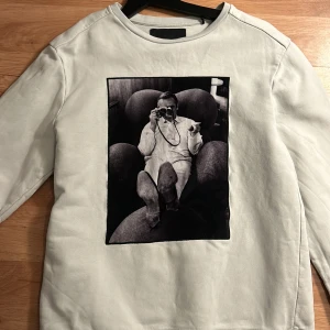  Limitato tröja  - Vit sweatshirt från Limitato med stort svartvitt fotoprint på framsidan. Tröjan har rund hals, lång ärm och mjukt bomullsmaterial. Limitato-logga broderad i nacken.