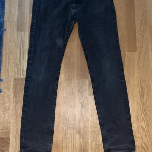 Svarta slim jeans i stretch - Säljer ett par svarta slim jeans med smal passform och klassisk femficksdesign. Jeansen är i stretchigt material för extra komfort och har en mörk tvätt som ger en clean look.