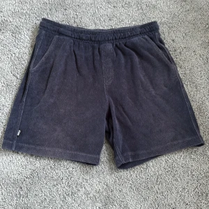 Mörkblå mysshorts från Warp - Snygga mörkblå shorts från Warp i mjuk frotté. De har elastisk midja, två sidofickor och en enkel, loose passform. Perfekta för chill dagar eller när du vill ha något bekvämt och stilrent. Klassisk look med diskret Warp-logga på benet.
